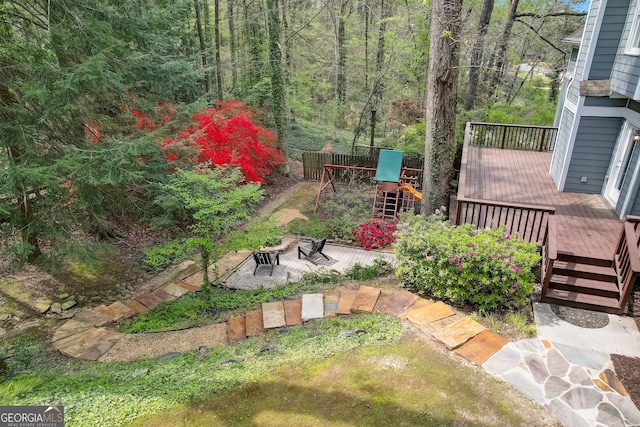 view of yard featuring a playground, a deck, and a patio