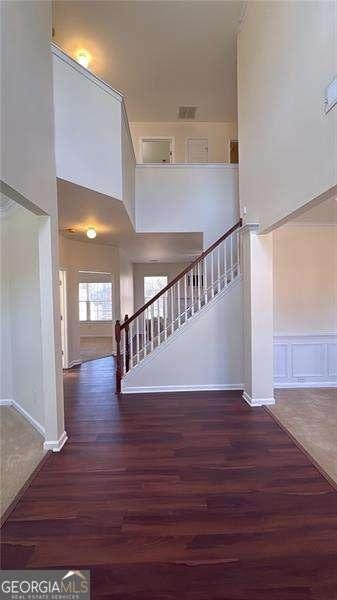 staircase featuring wood-type flooring and a high ceiling