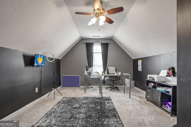 carpeted home office featuring vaulted ceiling, ceiling fan, and a textured ceiling