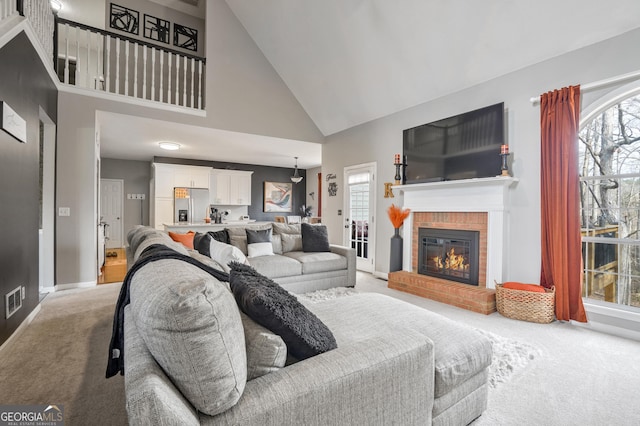 living room with a brick fireplace, light carpet, and a high ceiling