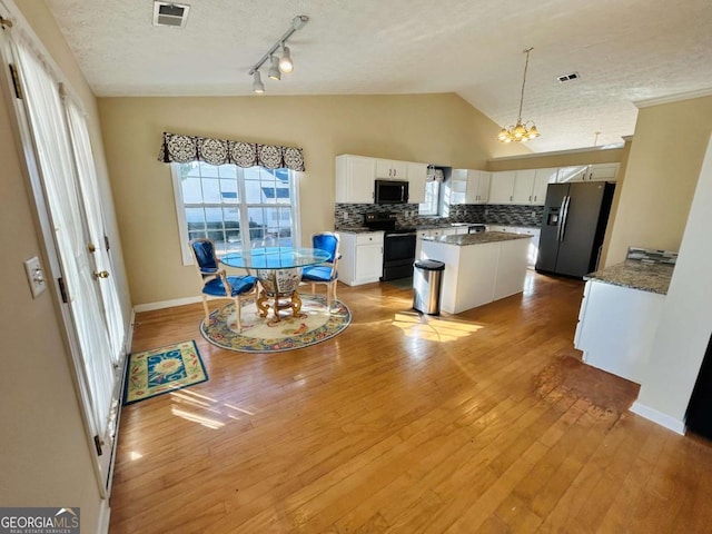 kitchen with black appliances, a center island, white cabinets, pendant lighting, and lofted ceiling