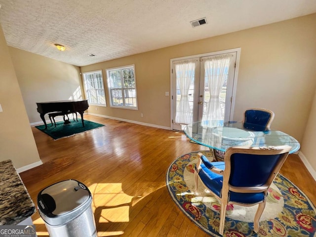 dining space featuring french doors, hardwood / wood-style floors, and a textured ceiling