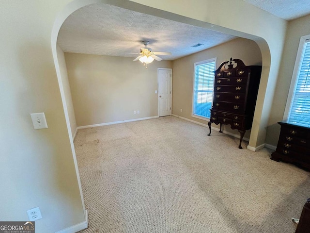 interior space with ceiling fan, light colored carpet, and a textured ceiling