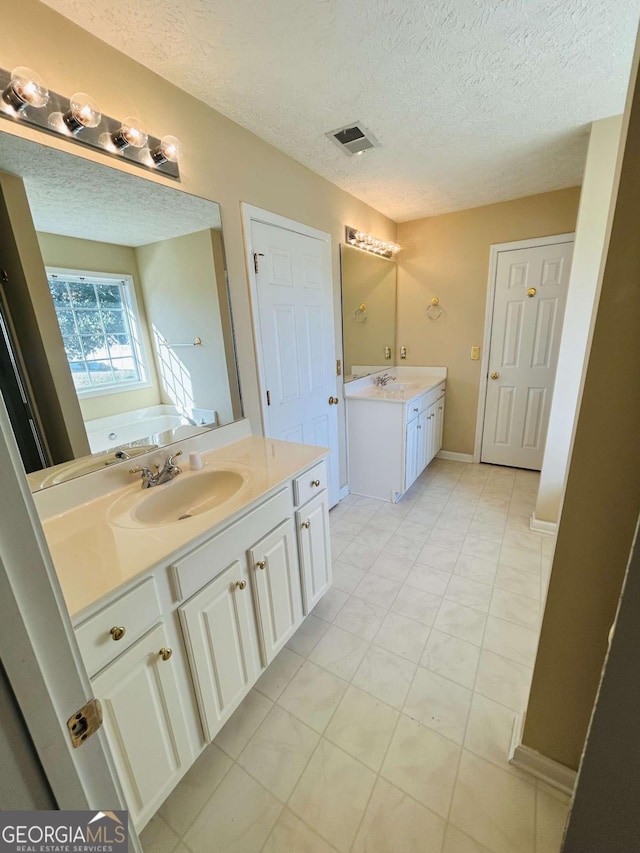 bathroom featuring vanity, a bathtub, tile patterned floors, and a textured ceiling