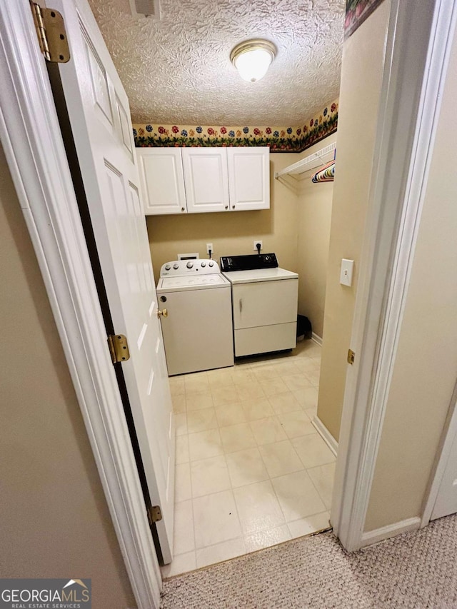 laundry room featuring washing machine and dryer, cabinets, and a textured ceiling