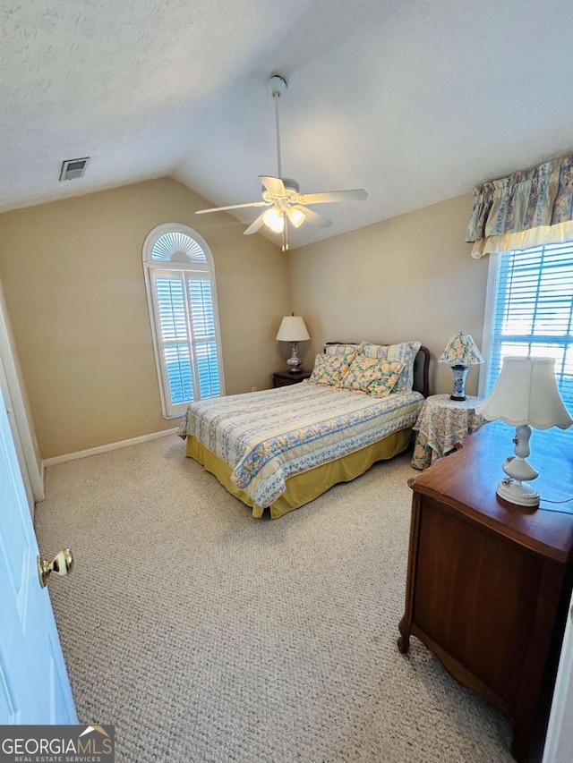 bedroom featuring multiple windows, a textured ceiling, vaulted ceiling, and ceiling fan