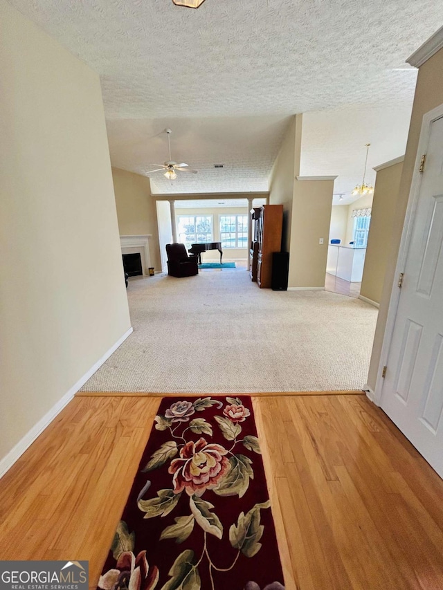 hall with a notable chandelier, carpet floors, and a textured ceiling