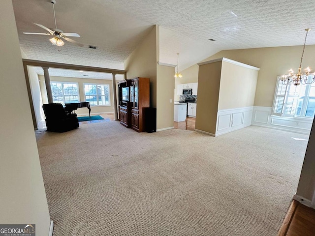 unfurnished living room featuring light colored carpet, a textured ceiling, and vaulted ceiling