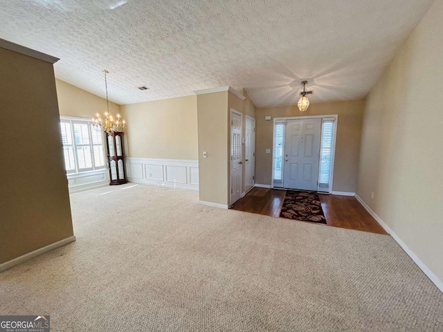 carpeted foyer featuring a chandelier, a textured ceiling, and lofted ceiling