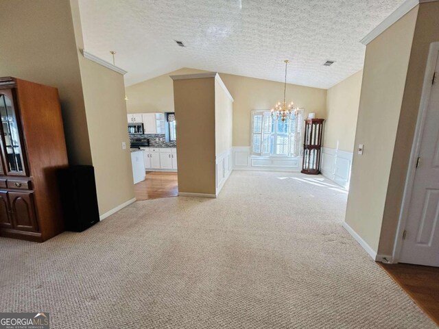 unfurnished dining area with light colored carpet, a textured ceiling, lofted ceiling, and a notable chandelier