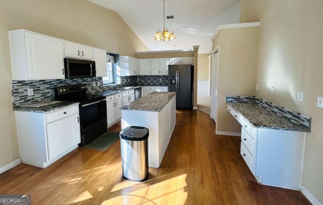 kitchen featuring white cabinets, a kitchen island, decorative light fixtures, stainless steel appliances, and lofted ceiling