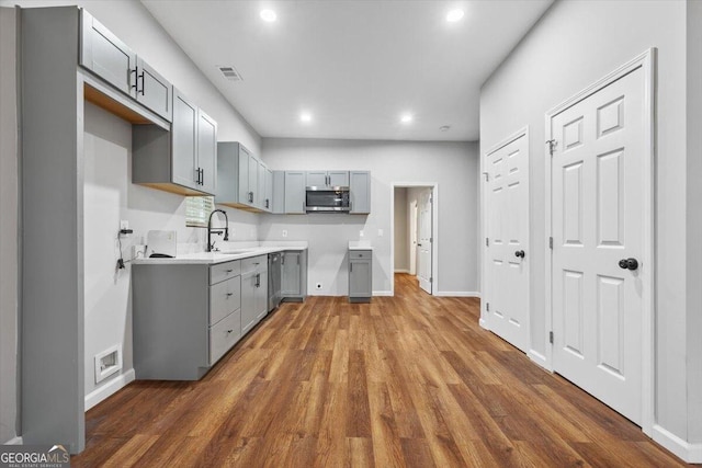 kitchen with dark wood-type flooring, appliances with stainless steel finishes, gray cabinetry, and sink