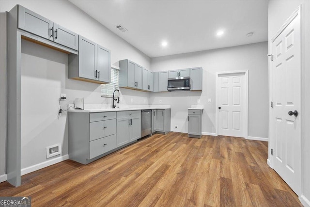 kitchen featuring sink, gray cabinets, dark wood-type flooring, and appliances with stainless steel finishes