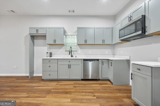 kitchen featuring light hardwood / wood-style floors, sink, appliances with stainless steel finishes, and gray cabinetry