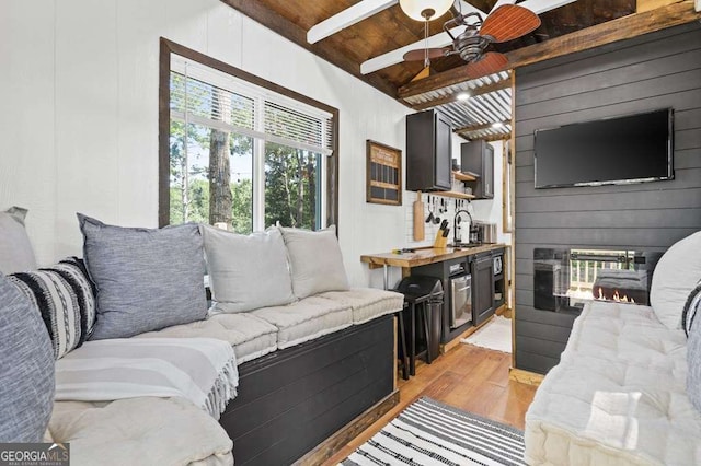 living room featuring wood ceiling, vaulted ceiling with beams, a large fireplace, wood walls, and light hardwood / wood-style flooring