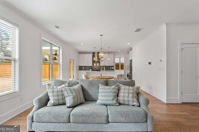 living room featuring a chandelier, a healthy amount of sunlight, and crown molding