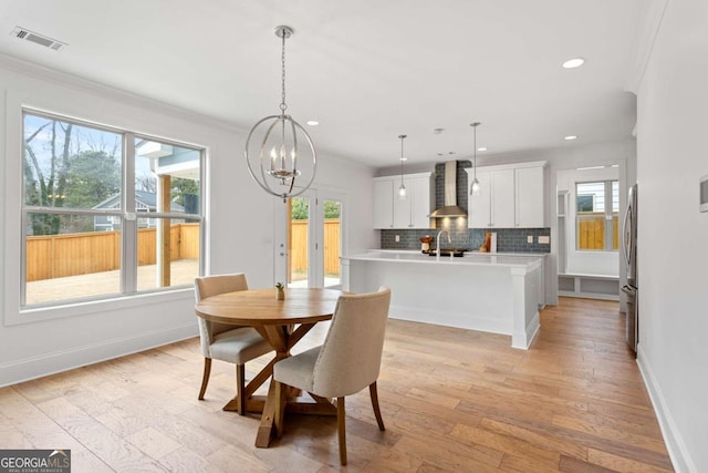 dining room with ornamental molding, sink, light hardwood / wood-style flooring, and plenty of natural light