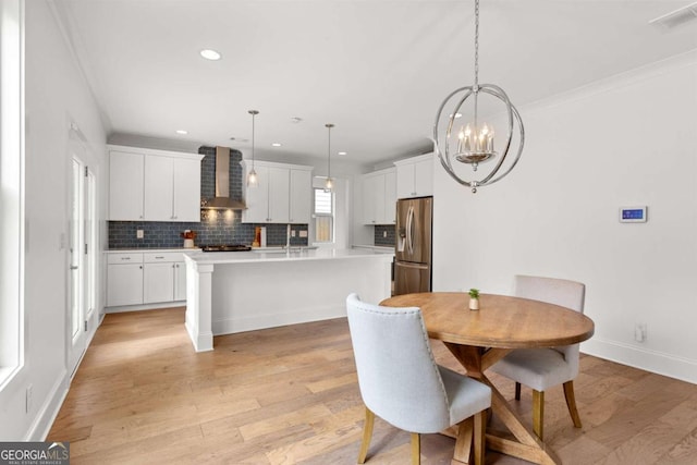 dining room with light hardwood / wood-style flooring, crown molding, and an inviting chandelier