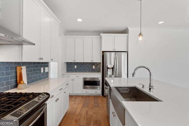 kitchen featuring hanging light fixtures, appliances with stainless steel finishes, sink, white cabinets, and hardwood / wood-style floors