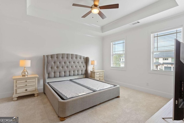 bedroom with light colored carpet, ceiling fan, and a raised ceiling