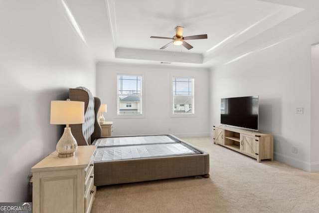 bedroom featuring ceiling fan, light colored carpet, and a tray ceiling