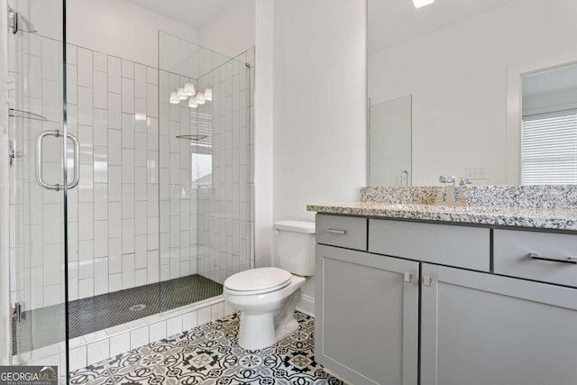 bathroom with vanity, toilet, a shower with shower door, and tile patterned flooring