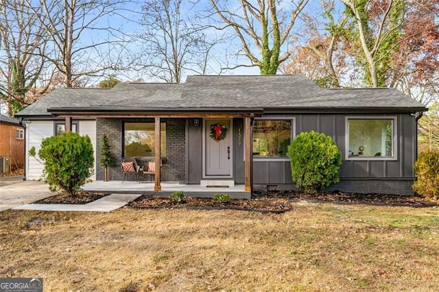 single story home with covered porch, a front yard, and central AC unit