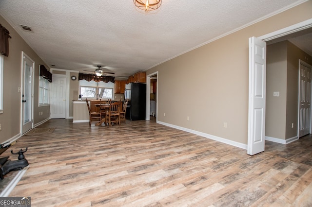 unfurnished living room with crown molding, light wood-type flooring, a textured ceiling, and ceiling fan