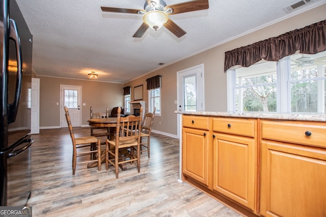 dining space featuring a textured ceiling, light hardwood / wood-style flooring, and crown molding