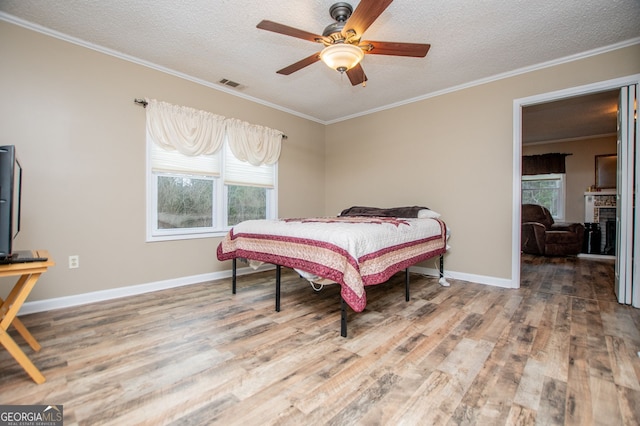 bedroom featuring ceiling fan, wood-type flooring, crown molding, and a textured ceiling