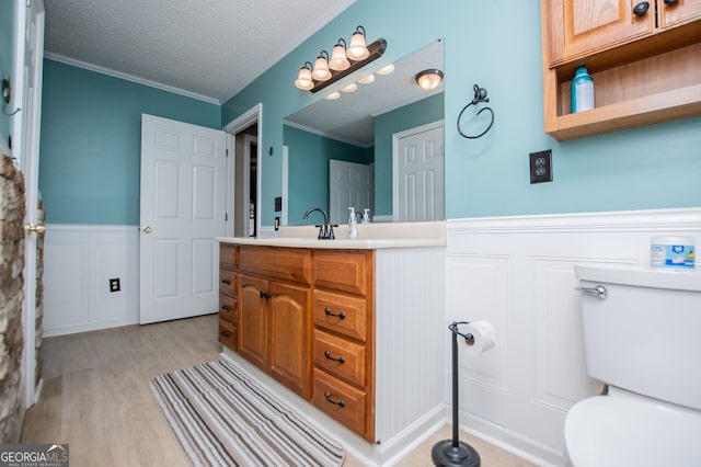 bathroom with toilet, ornamental molding, a textured ceiling, and wood-type flooring