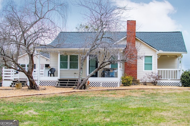 back of house featuring covered porch and a yard