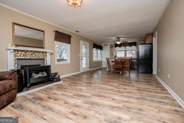 living room with ceiling fan, a textured ceiling, crown molding, and light wood-type flooring