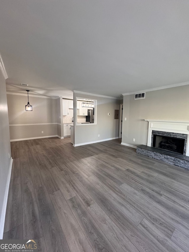 unfurnished living room with crown molding, a stone fireplace, and hardwood / wood-style flooring