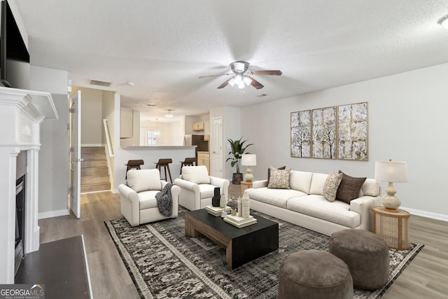 living room with hardwood / wood-style flooring, a textured ceiling, and ceiling fan