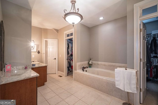 bathroom featuring vanity, a relaxing tiled tub, and tile patterned flooring