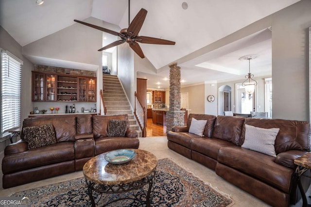 living room featuring ceiling fan, decorative columns, indoor bar, and vaulted ceiling