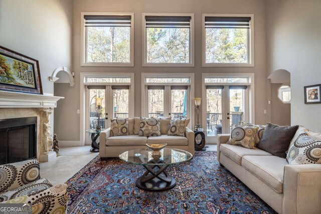 living room with a towering ceiling, a premium fireplace, and french doors