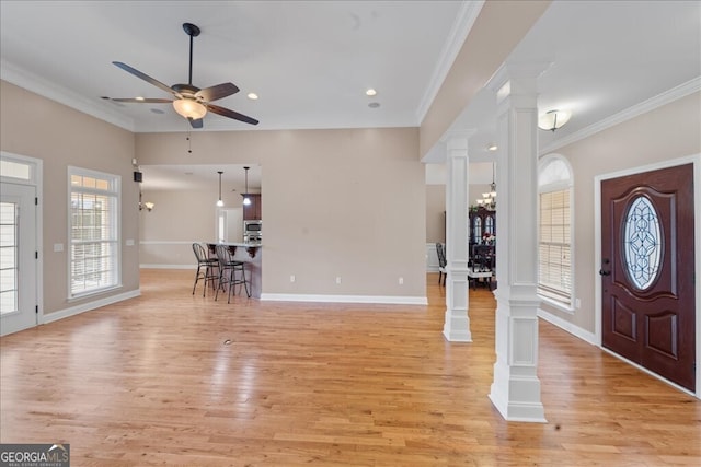 entryway with decorative columns, ceiling fan with notable chandelier, light wood-type flooring, and ornamental molding