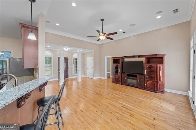 living room with crown molding, decorative columns, light hardwood / wood-style flooring, and ceiling fan