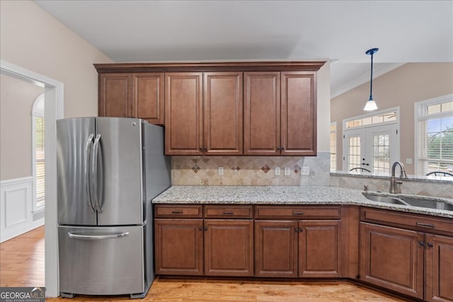 kitchen with sink, light stone counters, tasteful backsplash, and stainless steel fridge