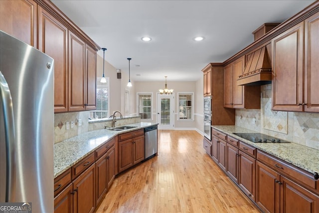 kitchen with appliances with stainless steel finishes, sink, hanging light fixtures, light wood-type flooring, and custom range hood