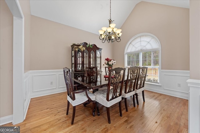 dining area with light wood-type flooring, a chandelier, and lofted ceiling