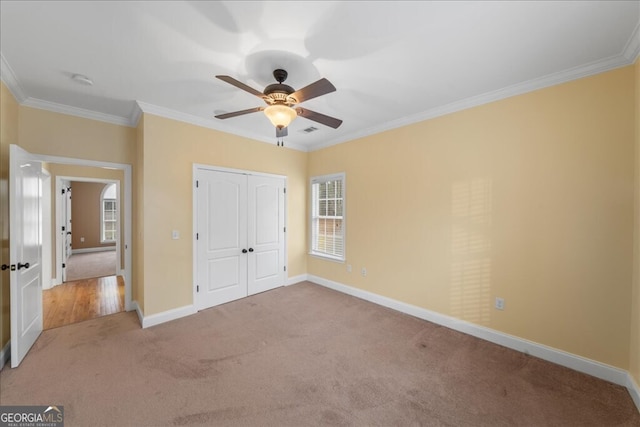 unfurnished bedroom featuring crown molding, light carpet, a closet, and ceiling fan