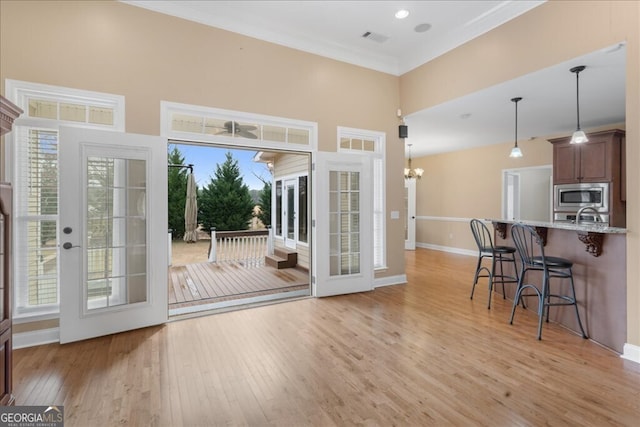 entryway with sink, an inviting chandelier, ornamental molding, and light wood-type flooring