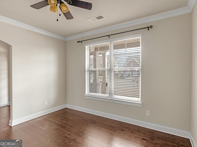 empty room with a healthy amount of sunlight, visible vents, crown molding, and wood finished floors