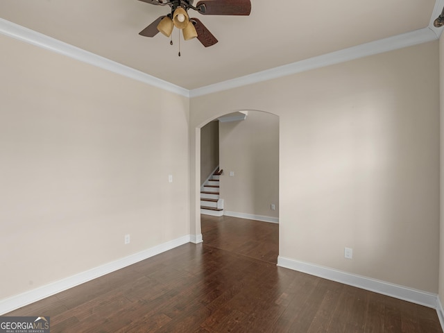 empty room with baseboards, arched walkways, a ceiling fan, dark wood finished floors, and crown molding