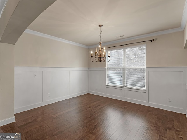 unfurnished dining area with a wainscoted wall, ornamental molding, dark wood-style flooring, and visible vents