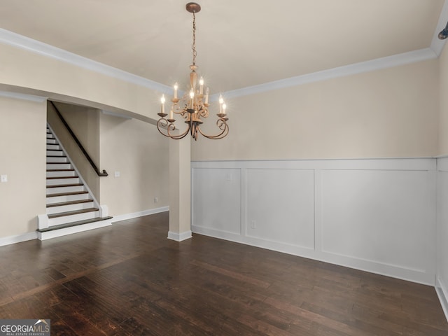 unfurnished dining area featuring stairs, ornamental molding, dark wood-style flooring, and a decorative wall