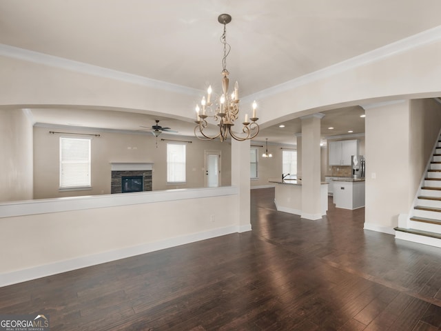 unfurnished living room with ornamental molding, dark wood finished floors, baseboards, and stairs